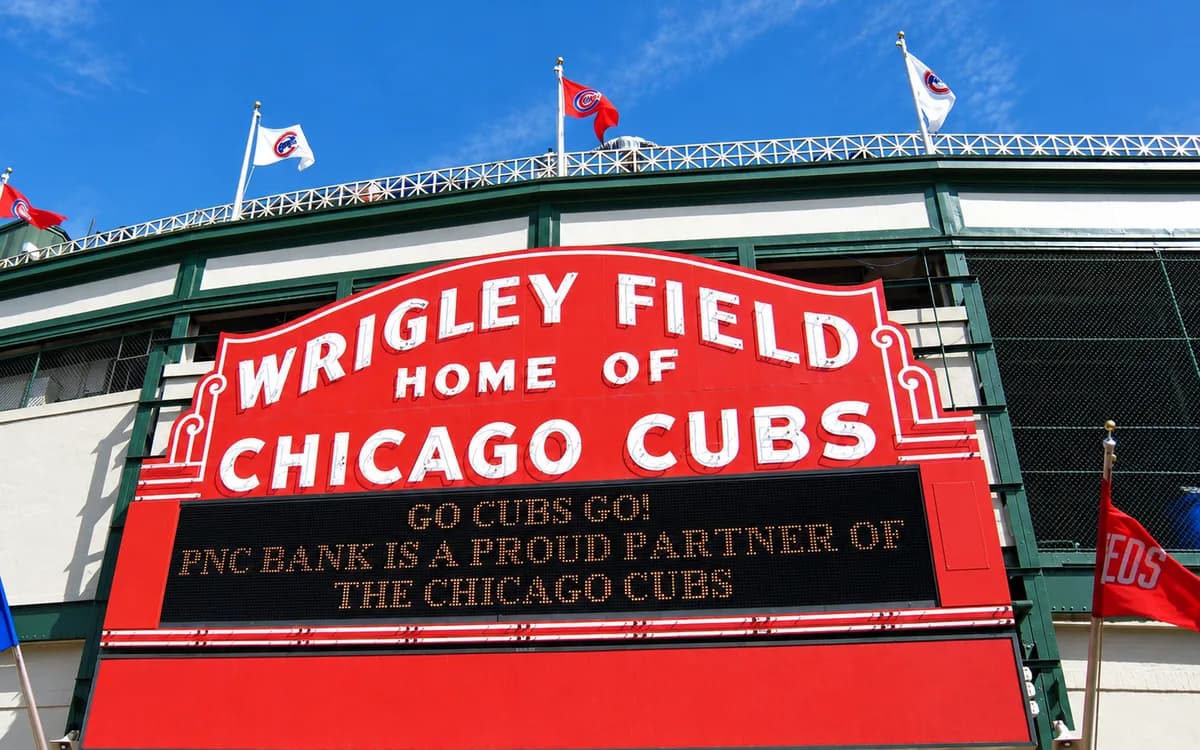 The red Wrigley Field marquee reading 'Wrigley Field, Home of Chicago Cubs' beneath the ballpark's flags