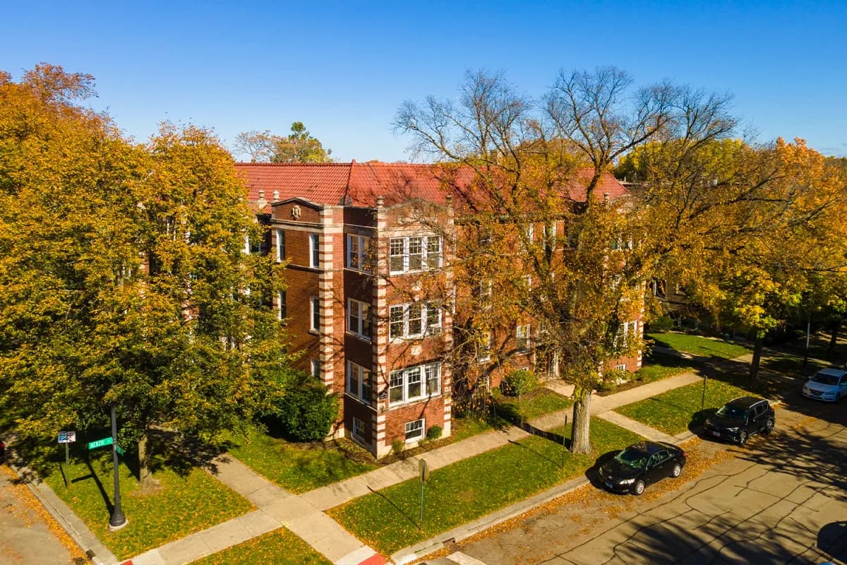 Vintage red-tile-roof apartment building surrounded by autumn trees — 325-31 Kedzie St, Evanston, TBS Properties